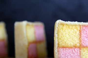 Freshly cut Battenberg Cake slices with dark background. Pink and yellow sponge covered in marzipan