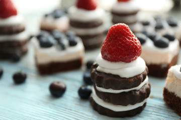 Delicious strawberry and blueberry cakes on wooden table