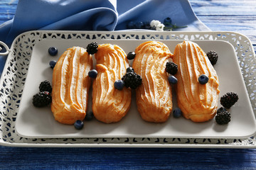 Tasty eclair with berries on a tray