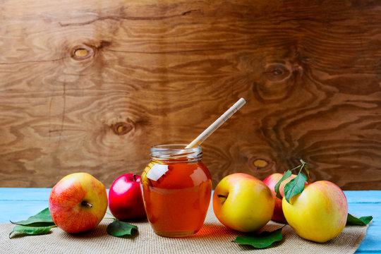 Glass honey jar with dipper and fresh apples, copy space