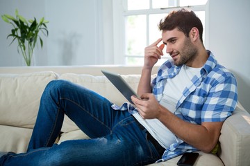 Man using digital tablet while relaxing on sofa