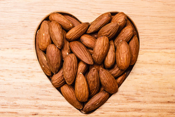 Heart shaped almonds on wooden surface background