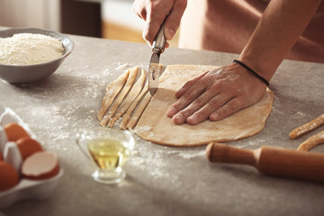 Male hands preparing pasta on kitchen table