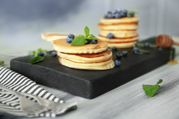 Delicious pancakes with blueberries and mint on wooden cutting board