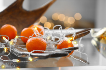 Mandarins with garland lights on table in decorated room