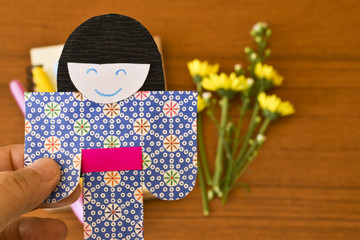 Origami Japanese doll, colorful Japanese paper doll and yellow flower in background