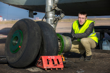 Obraz na płótnie Canvas Engineer fixing aircraft's wheel
