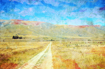 Dirt road leading through meadows to mountains in the distance. Summer in the New Zealand countryside. Grunge, vintage textured image.
