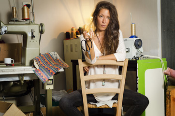 Beautiful fashion designer girl, posing in her workshop, holding scissors