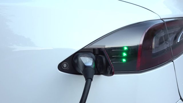 CLOSE UP: Tesla electric autonomous car filling batteries at supercharger
