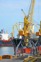 Obraz premium Bulk cargo ship under port crane