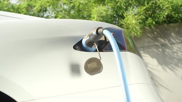 CLOSE UP: Tesla electric car charging on socket at home yard on sunny day