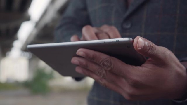 4K movement stabilized Close up of unrecognizable afro american man holds tablet computer and using touch screen to browse a content