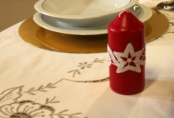 Red candle with Christmas embroidery on the table of the restaur