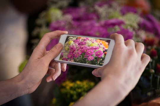 Woman's hand taking photograph of flower bouquet