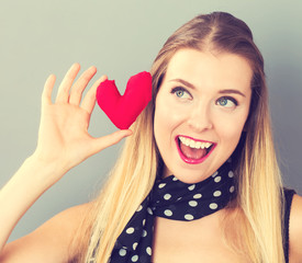 Happy young woman holding a heart cushion