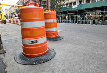 A traffic barricade of orange barrels indicates a site of road construction work in Manhattan.