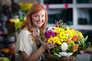 Fototapeta premium Happy female florist holding basket of flowers
