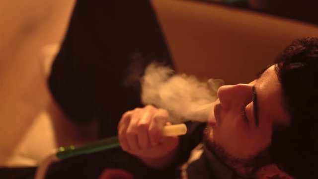 young bearded man smokes a hookah closeup