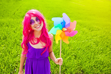 optimistic young woman wearing pink wig posing outdoors with win