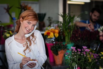 Female florist taking an order on telephone