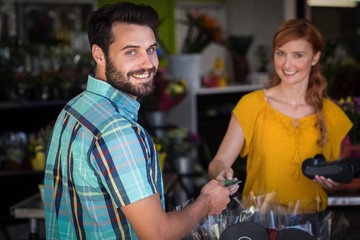 Man making payment with his credit card to female florist
