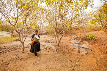 african carrying a drum in a forest