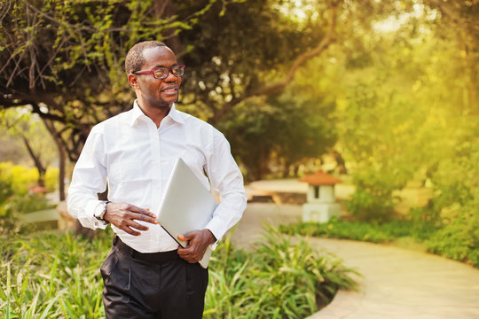 African American Businessman Carrying Laptop Walking In A Park