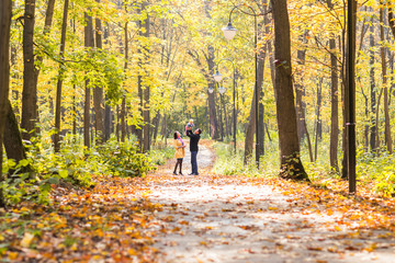 Fototapeta premium happy young family with their daughter spending time outdoor in the autumn park
