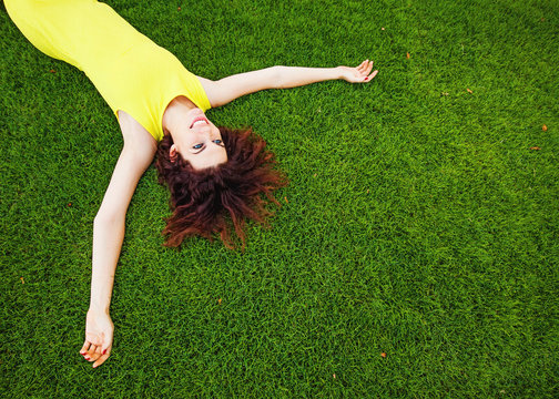 cheerful woman wearing bright dress lying down on a grass