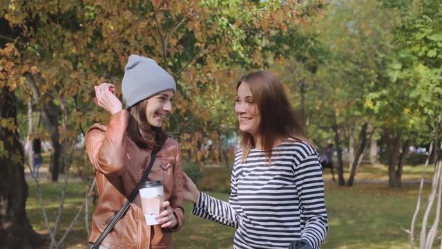 two young women take a selfie in autumn Park