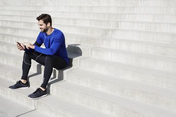 Athlete sitting on steps using smartphone