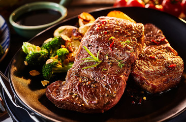 Two pieces of cooked sirloin steak with veggies