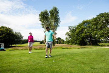 Fototapeta premium Male instructor assisting woman in learning golf
