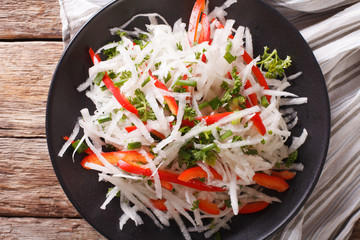 Tasty salad of daikon with pepper and herbs closeup on a plate. horizontal top view