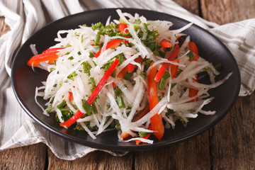 Tasty salad of daikon with pepper and herbs closeup. horizontal