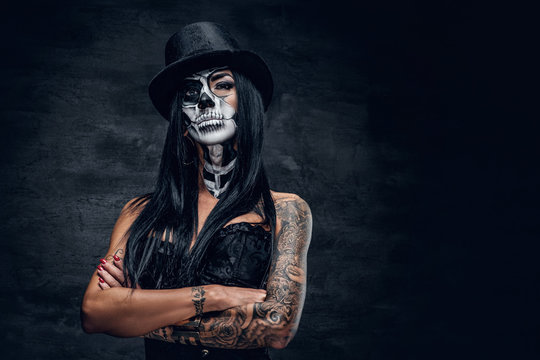 A girl in stylish top hat with skull make up.