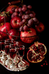 Still life on a dark background. Wine (liquor) glasses, fruits a