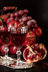Still life on a dark background. Wine (liquor) glasses, fruits a