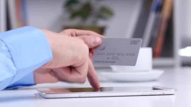 Man shopping online using digital tablet and credit card. Close up