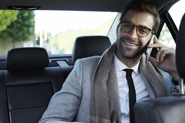Businessman on call in car, smiling