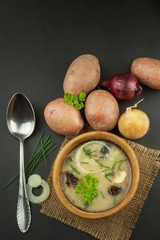 Homemade potato soup with mushrooms. Bowl with potato soup on wooden table. Food preparation.
