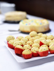 buffet with muffins or vanilla cupcakes and other dessert cakes. Selective focus on the foreground.
