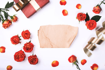Red roses with red gift and blank sheet of paper