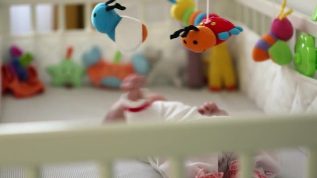 infant baby playing with stuffed toys rotating over bed