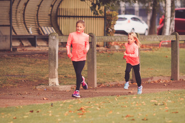 Two young girls running on athletic race track
