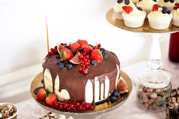 Birthday cake with cream and chocolate, fresh fruit and berries slide.