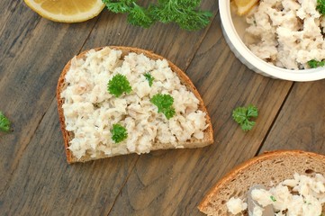 Healthy spread from fish, lemon and parsley with bread on brown wooden background