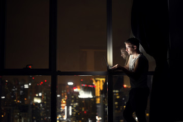 Fototapeta na wymiar Young designer working on laptop at night near window with beautiful view.