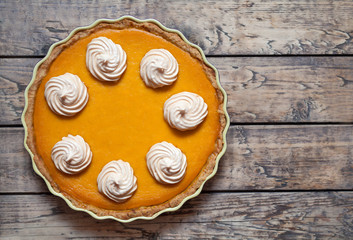 Fototapeta na wymiar Traditional Homemade Delicious Pumpkin pie with whipped cream and spices made for Thanksgiving, Halloween, top view.